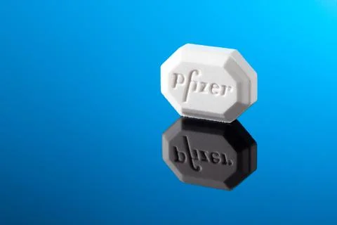 Close-up of white Pfizer tablet on blue background. Illustrates modern phar.. Stock Photos