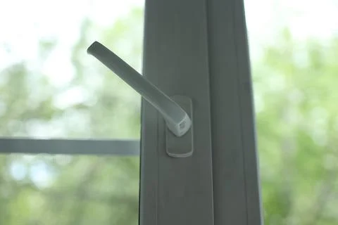 Close up of a white plastic window handle turned to an open position against a Stock Photos