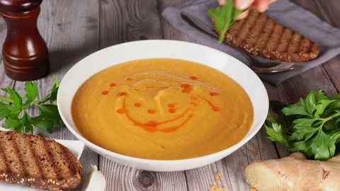 Close up of a white plate with warm orange lentil cream soup Stock Footage 136873221