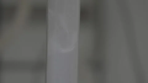 Close-up of white powder flowing through a transparent vertical tube 스톡 동영상 327633540