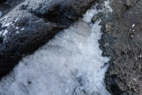 A close-up of a white quartz vein embedded in a dark porous volcanic rock s.. Stock Photos