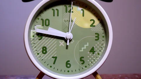 Close-Up of a White Retro Alarm Clock on a Wooden Table Stock Footage 337386376