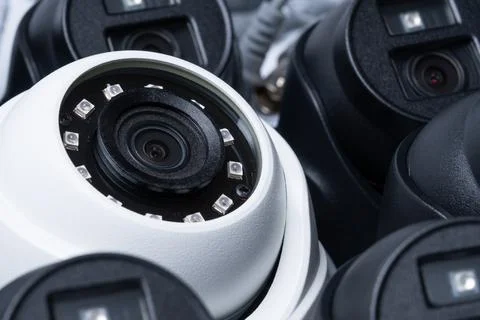 Close-up white security camera with black cameras nearby. Stock Photos