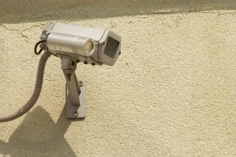 Close-up white security surveillance camera on the wall of a apartment house. Stock Photos