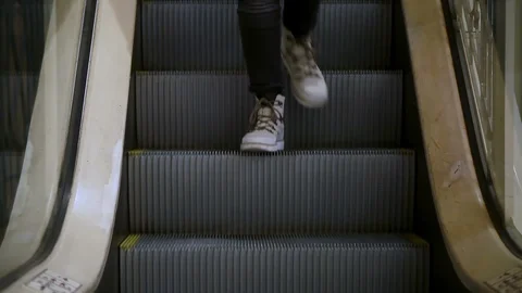 Close-up of White shoes going down the steps of an escalator that goes the other Stock Footage 114251060