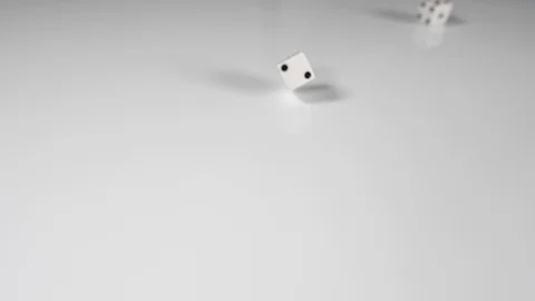 Close up of a white single dice spinning onto a white surface background, above Stock Footage 89187673