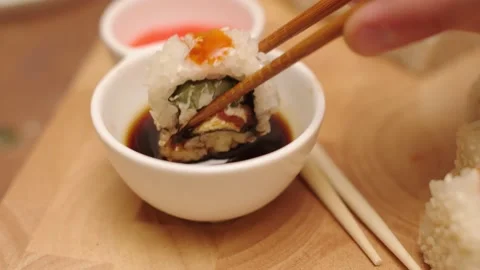 Close up of a white up with soy sauce in which a California roll of rice, cheese Stock Footage 143131900