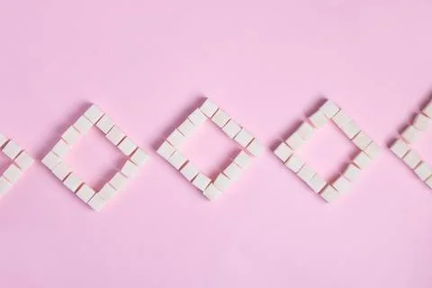 Close up of white sugar cubes on pink paper, top view sweet Stock Photos