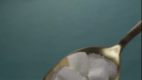 Close-up of white sugar cubes resting on a golden spoon Stock Footage 285489385