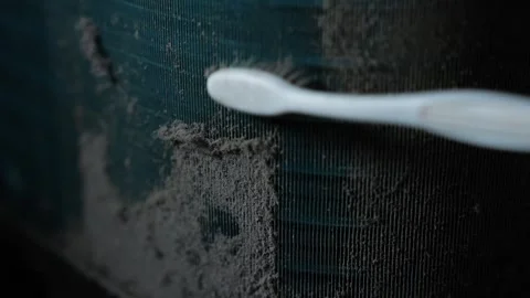 Close-up of a white toothbrush brushing thick dust from a dark air vent or .. Stock Footage 338319352