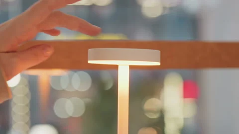 Close up of white touch sensitive modern tall table lamp with hand turning on Stock Footage 345065646