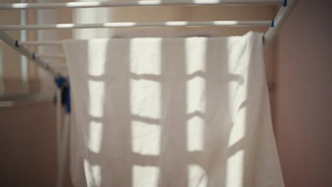 Close up of a white towel hanging on a foldable indoor drying rack, with soft 스톡 동영상 335274116