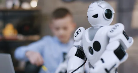 Close up of the white toy robot in front of the camera, and blurred teen small Stock Footage 135842199