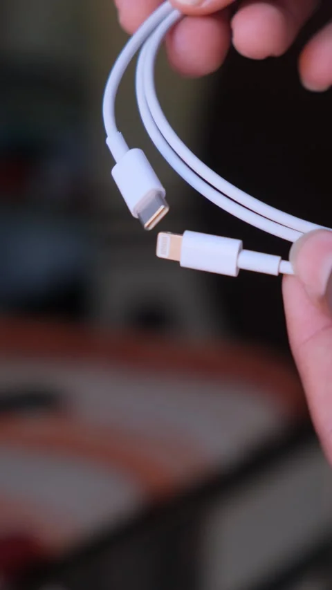 Close up of a white USB-C to Lightning charging cable held by hand Stock Footage 332654224
