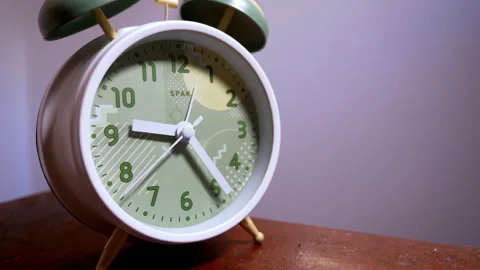 Close-Up of a White Vintage Alarm Clock on a Rustic Wooden Table Stock Footage 337394547