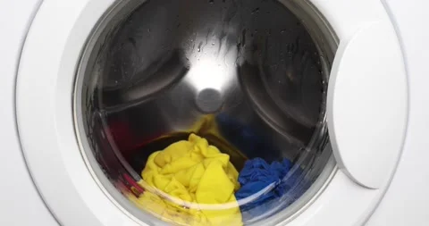 Close-up white washing machine washes multicolored, red, yellow and blue. Stock Footage 146714304