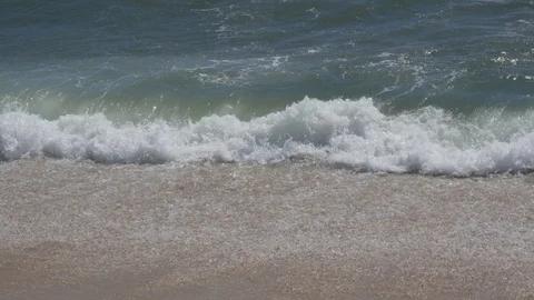 Close up of white waves crashing on a sandy beach in summer Stock Footage 95176673