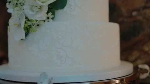 Close-up of a white wedding cake with delicate floral patterns and an Stock Footage 284907557