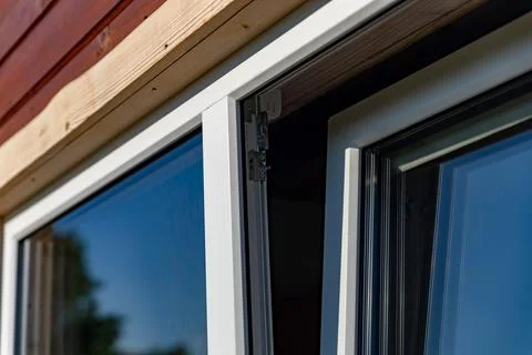 Close-up of a white window frame with a metal hinge and a chain mechanism. .. Stock Photos