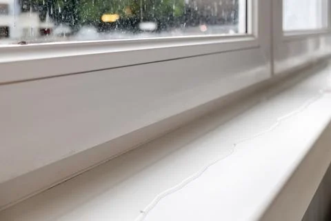 Close up of white window frame with a window sill, which spreads a puddle. .. 스톡 사진