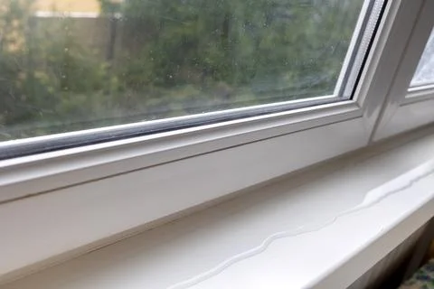 Close up of white window frame with window sill, which spreads a puddle. Th.. Stock Photos