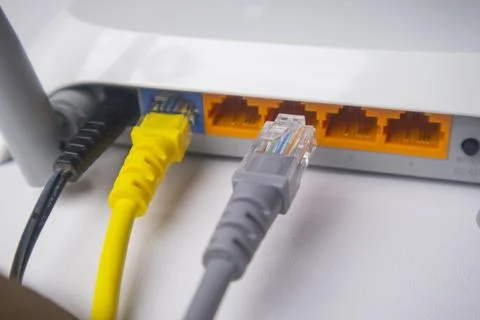 Close-up of a white wireless router back panel with one yellow Ethernet cab.. Stock Photos