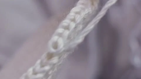 Close-up of white yarn being knitted into a textured pattern, showcasing the Video stock 330939863