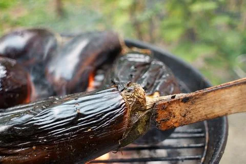 Close-up of whole eggplants roasting over hot coals on a charcoal grill Stock Photos