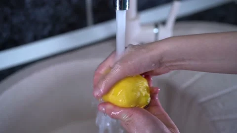 Close-up of whole lemon falling into water. Action. Whole lemon falls into water Stock Footage 154413736