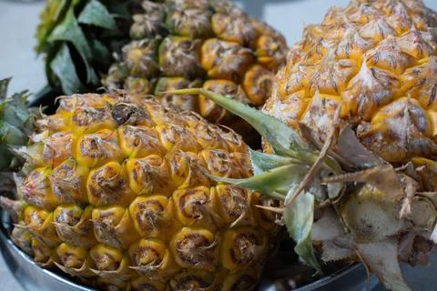 Close up of whole pineapples with yellow rough skin and green leaves Stock Photos