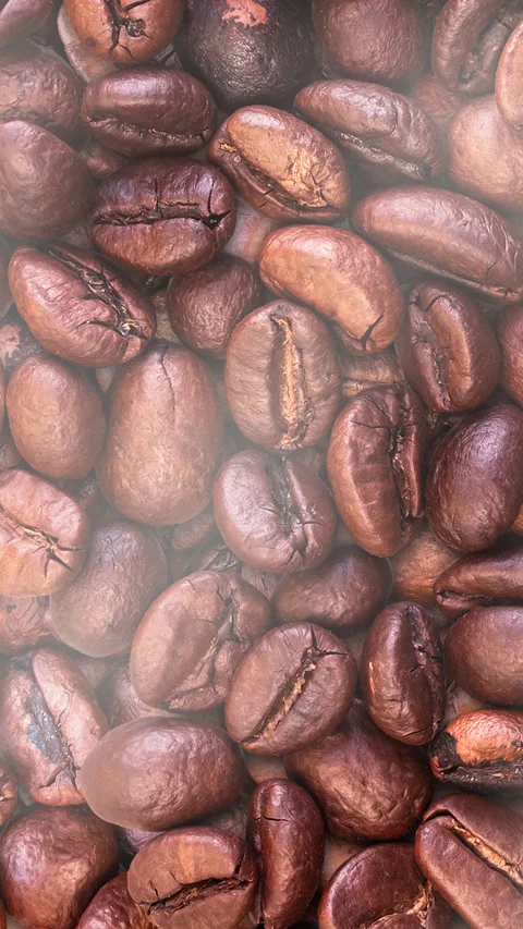 Close-up of whole roasted coffee beans with smoke rising and dissipating. Stock Footage 304654794