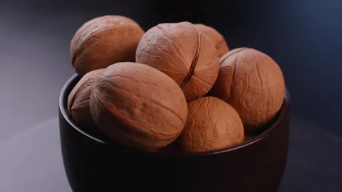 Close-up of Whole Walnuts Resting in Black Bowl Видео 336560316