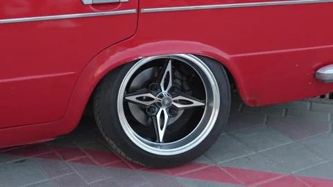 Close-up of wide custom rim on stretched tire of red vintage car. Stock Footage 341137626
