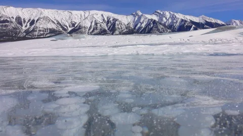 CLOSE UP: Wind blows snowflakes across the frozen lake full of methane bubbles Stock Footage 122814042