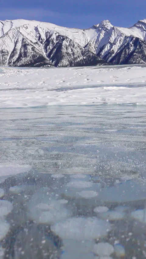 CLOSE UP: Wind blows snowflakes across the frozen lake full of methane bubbles Stock Footage 311579992