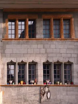 Close-up of windows with ceramic flower pots and stone wall. Foto stock