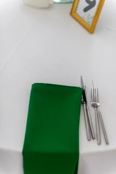 Close up of wine glasses, silver tableware and green napkins on round table.. Stock Photos