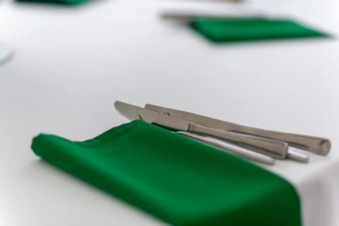 Close up of wine glasses, silver tableware and green napkins on round tables  Stock Photos