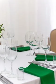 Close up of wine glasses, silver tableware and green napkins on round tables  Fotos de archivo