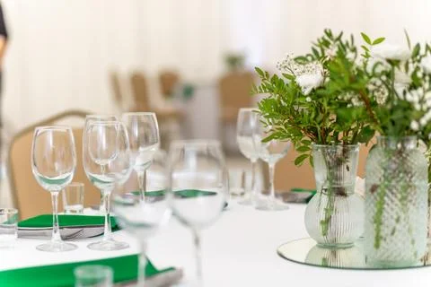 Close up of wine glasses, silver tableware and green napkins on round table.. Stock Photos