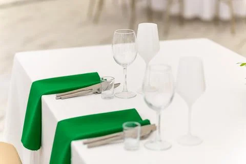 Close up of wine glasses, silver tableware and green napkins on round tables  Stock Photos