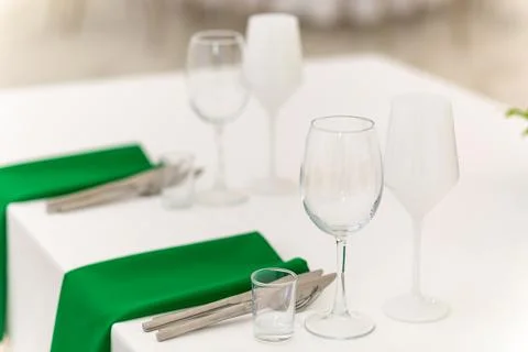 Close up of wine glasses, silver tableware and green napkins on round tables  Stock Photos