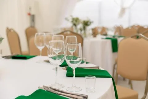 Close up of wine glasses, silver tableware and green napkins on round tables  Stock Photos
