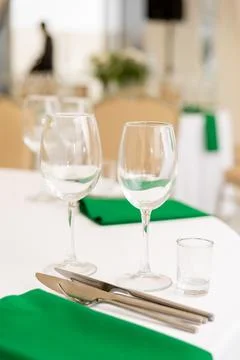 Close up of wine glasses, silver tableware and green napkins on round table.. Stock Photos