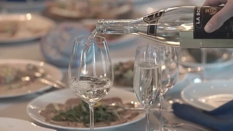 Close-up of wine glasses on a table.  wine is poured from a bottle into a glass Stock Footage 123541634