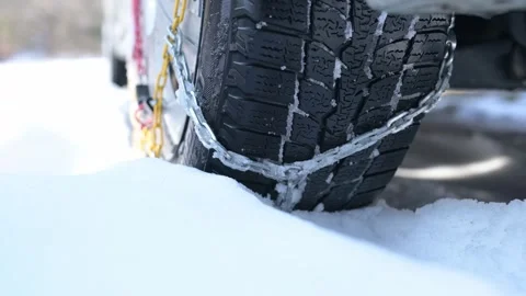 Close-up of a winter tire with snow chains gripping deep snow. The detailed Stock Footage 303574988