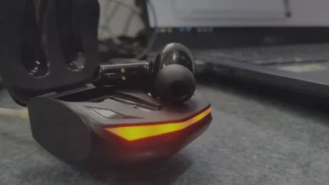 Close-up of wireless earbuds charging in stylish case under natural lightin.. Stock Footage 325411642