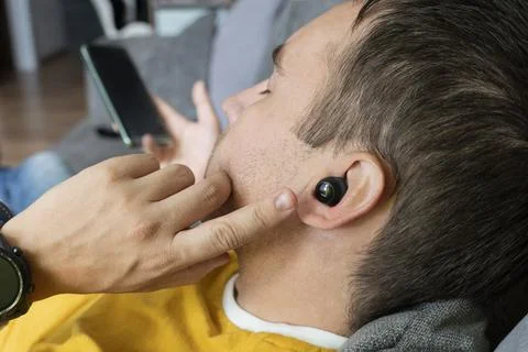 Close-up of wireless earphone in human ear on dark background. insert the ear Stock Photos