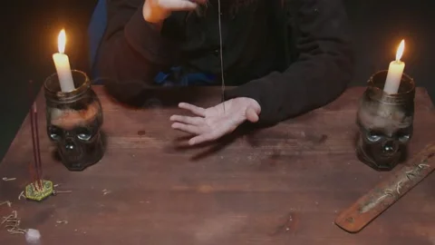 Close up of witch female fortune teller uses needle with thread to magic Stock Footage 145684538