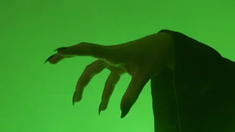 Close-Up of a Witch's Hand with Long Black Nails Against a Green Background Stock Footage 289018080